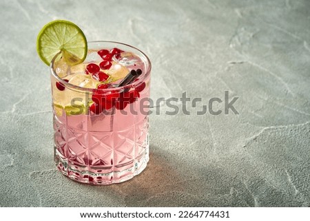 Alcoholic pink cocktail with cranberry and ice in a glass. Concrete background. Vermouth with vodka