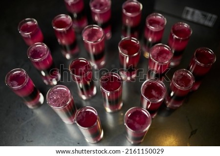 a lot of alcoholic shots of red cocktails on a dark background