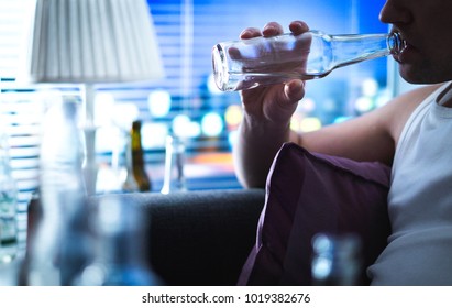 Alcoholic Sipping Bottle. Alcoholism And Alcohol Abuse Concept. Drunken Man Sitting Home On Couch. Unemployed Sad Guy Drinking On Sofa. Taking A Sip In The Middle Of The Night.