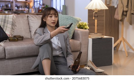 Alcoholic Woman Getting Off Work Is Guzzling Beer And Switching Channel With Tv Remote In The Living Room. Genuine Lifestyle