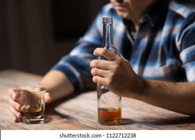 Alcoholism, Alcohol Addiction And People Concept - Male Alcoholic With Bottle And Glass Drinking Whiskey At Night