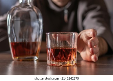 Alcoholism, alcohol addiction and people concept - male alcoholic pulls his hand to a glass of alcohol.