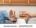 Alcoholism, depressed asian young man refuse, push out alcoholic beverage glass, drink whiskey, sitting alone at night. Treatment of alcohol addiction, having suffer abuse problem alcoholism concept.