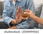 Alcoholism, depressed asian young man refuse, push out alcoholic beverage glass, drink whiskey, sitting alone at night. Treatment of alcohol addiction, having suffer abuse problem alcoholism concept.