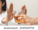 Alcoholism, depressed asian young woman hand refuse alcoholic beverage, drink whiskey while person holding glass give to her. Treatment of alcohol addiction, having suffered abuse problem alcoholism.