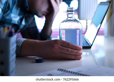 Alcoholism or drinking problem concept. Alcoholic with vodka bottle on table. Man and alcohol late at night. Drunk at work or in home office.