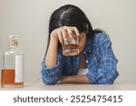 Alcoholism drunk asian young woman hand holding glass of alcohol or whiskey, female sitting alone, drinking on table at home, at night. Treatment of alcohol addiction, suffer abuse problem alcoholism