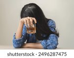 Alcoholism drunk, sad asian young woman hand holding glass of alcohol or whiskey, alone depressed female drink booze on background. Treatment of alcohol addiction, suffer abuse problem alcoholism.