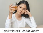 Alcoholism drunk, sad asian young woman fell asleep hand holding glass of alcohol or whiskey, alone depressed alone female drink booze. Treatment of alcohol addiction, suffer abuse problem alcoholism.