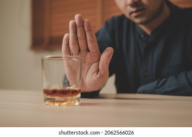 Alcoholism, Sad Depressed Asian Young Man Refuse, Push Alcoholic Beverage Glass, Drink Whiskey, Sitting Alone At Night. Treatment Of Alcohol Addiction, Having Suffer Abuse Problem Alcoholism Concept.