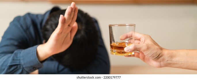 Alcoholism, Sad Depressed Asian Young Man Refuse, Push Alcoholic Beverage Glass, Drink Whiskey, Sitting Alone At Night. Treatment Of Alcohol Addiction, Having Suffer Abuse Problem Alcoholism Concept.