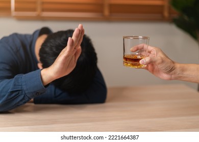 Alcoholism, Sad Depressed Asian Young Man Refuse, Push Alcoholic Beverage Glass, Drink Whiskey, Sitting Alone At Night. Treatment Of Alcohol Addiction, Having Suffer Abuse Problem Alcoholism Concept.