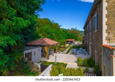 Ales, France - August 24th 2022 : Aerial View By Drone Of An Exterior Of A Big House. A Light Stone Terrace With Wooden Patio, Vegetation, Trees, Blue Sky During Sunny Weather