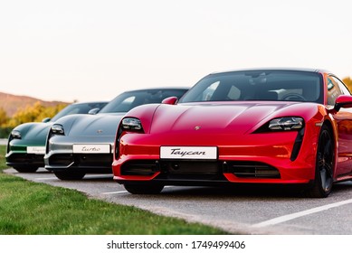 Alesund / Norway - May 31, 2020: Three luxury Porsche Taycan sedans in a parking lot, parked for promotional purposes. Shot from front.
