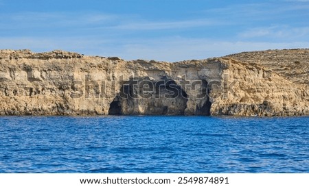 Alex Cave in limestone cliff in deep blue mediterranean sea under blue sky at Comino island of Malta