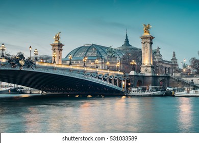 Alexander III Bridge at dusk with Grand Palais (Great Palace) on the background. It's a deck arch bridge, regarded as the most ornate, extravagant bridge in the city. 