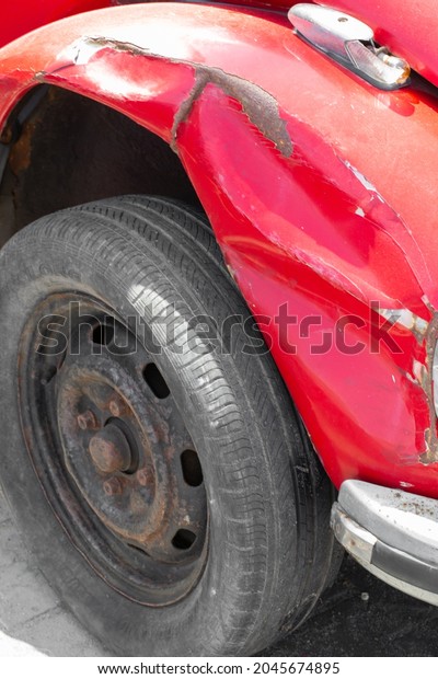 Alexandria, Egypt-September 20, 2021:\
Red beetle vintage car with a dented rusty front\
fender