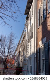 Alexandria, VA, USA 11-28-2020: A House  Painter Is On Top Of An  Extension Ladder Painting The Exterior Surface Of An Old Brick House. He Wears No Safety Equipment While Working At Height.