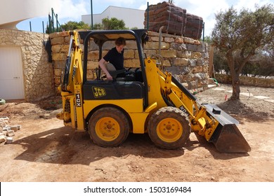 Algarve, Portugal 10 April 2019: A JCB mini digger being used to do landscaping work in a front garden