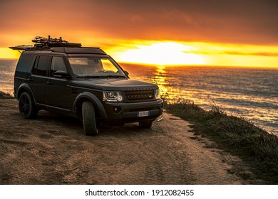 Algarve, Portugal - August 2020: Lifestyle photo of a black Land Rover Discovery 4 driving along scenic Portuguese coastline. Off-road vehicle during Beautiful sunset on summer evening.