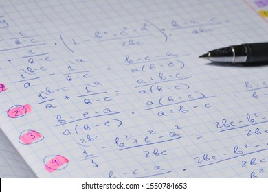 Algebraic calculations in open graph notebook with black pen. White paper with math fractions