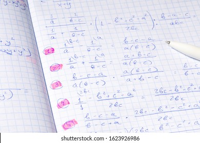 Algebraic calculations in open graph notebook with black pen. White paper with math fractions