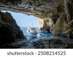 Alghero, Italy - August 25, 2023: Boat waiting for the tourist of the guide visit, view from inside the Grotto of Neptune (Grotta di Nettuno) on the island of Sardinia