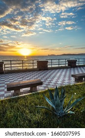 Alghero seafront under a cloudy sky at sunset. Sardinia, Italy