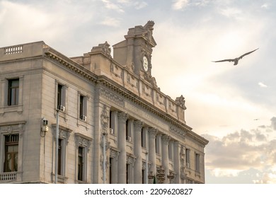 Algiers, Algeria - September 16, 2022: The Chamber Of Commerce Old Consular Palace With A French Written Engraving And A Clock On The Roof. Flying Bird, Cloudy Sky With Golden Hour Sunlight Background