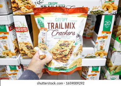 Alhambra, California/United States - 02/19/2020: A Hand Holds A Package Of Tropical Fields Crispy Trail Mix Crackers, On Display At A Local Big Box Grocery Store.