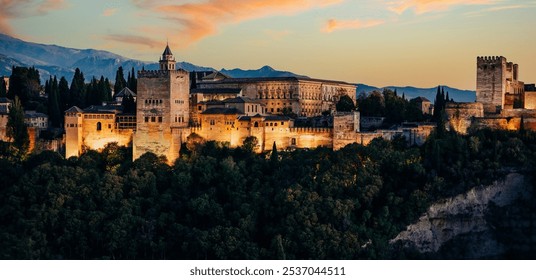 Alhambra palace, Granada, Spain. The alhambra palace and fortress complex is glowing in warm sunset light against a backdrop of mountains in granada, spain - Powered by Shutterstock