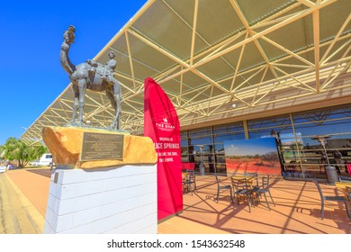 Alice Springs, Northern Territory, Australia - Aug 29, 2019: The Ghan Memorial: Statue Of Afghan Worker With Camel And Tables And Chairs Under The Lodge Station At Alice Springs.