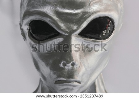 Alien face close up. Grey extraterrestrial race, silver face and big glossy black eyes. Sculpture, statue, contemporary art.