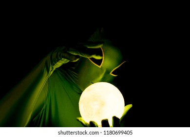 Alien with moon orb and dark background waving hand