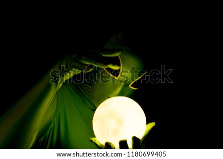 Alien with moon orb and dark background waving hand