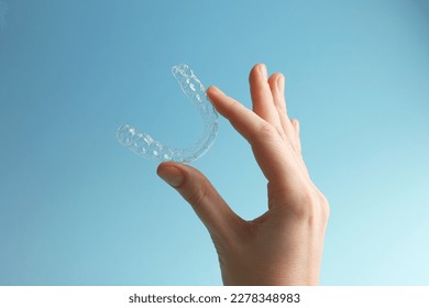 Aligners for aligning teeth on a blue background in a female hand