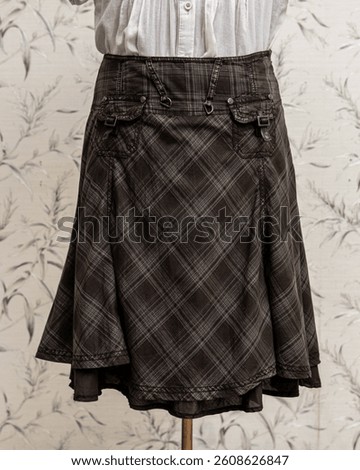 A-line skirt with patch pockets on dummy. Checkered pattern fabrics in dark grey color, Scottish tartan vibe.