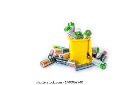  Alkaline Batteries In Yellow Garbage Container Isolated On White Background. Battery Recycling Concept. Copy Space.