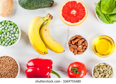 Alkaline food background, trendy Alkaline diet products - fruits, vegetables, cereals, nuts. oils, white marble background above copy space