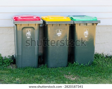 All 3 types of wheelie bin used in Brisbane against the wall of a house