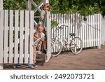 All the children open the gate to the fence of the country house and go out to the meeting. There is a bicycle on the fence.