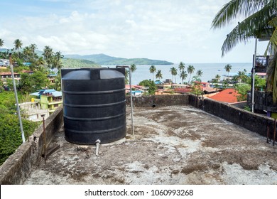All city roofs are occupied by black water storage tanks and different satellites. Water tank on the roof in Asia. Water heating tank against sea and the city. Asian water supply and heating system