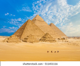 All Egyptian Pyramids from distance with row of camels walking in foreground in Giza, Cairo, Egypt.  Wide telephoto shot plenty of copy space.