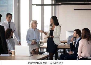 All Employees Attentive Listening Young Asian Female Colleague Gathered Together In Business Meeting Briefing At Coworking Area. Diverse International Company Staff Negotiating Having Busy Workday