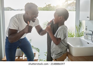 All freshened up and ready for an awesome day. Shot of a father showing thumbs up to his son while drying his face with a towel in a bathroom at home. - Powered by Shutterstock