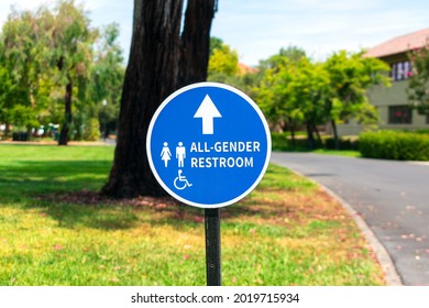 All Gender Restroom Outdoor Sign With Directional Arrow. ADA Compliant Gender Neutral Outdoor Signage. Blurred Public Park Background.