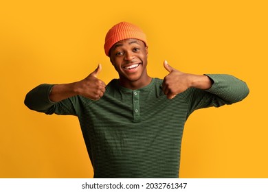 All Is Great. Cheerful Black Millennial Guy Showing Thumbs Up At Camera, Positive African American Hipster Man Gesturing Sign Of Approval, Recommending Something While Standing Over Yellow Background