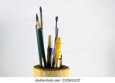 all kinds of writing utensils, drawings and painting in the place of the sincere tool made of bamboo on an isolated white background. there are pencils, pens, brushes and markers. 