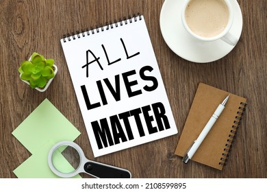 ALL LIVES MATTER    open notebook on the desktop next to a magnifying glass and two green stickers. Protest against the end of racism, anti-racism, equality. Poster on violation of human rights