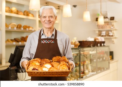 All made with love. Shot of a senior male baker holding a basket with freshly baked croissants just from the oven smiling to the camera senior man running his small business copyspace - Powered by Shutterstock